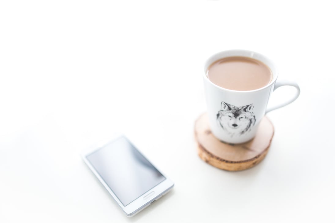 White desk with a cup of coffee and mobile phone